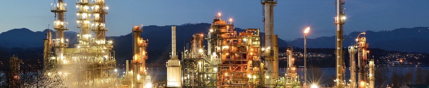 Night view of the Burnaby Refinery with the Burrard Inlet and mountains in the background.